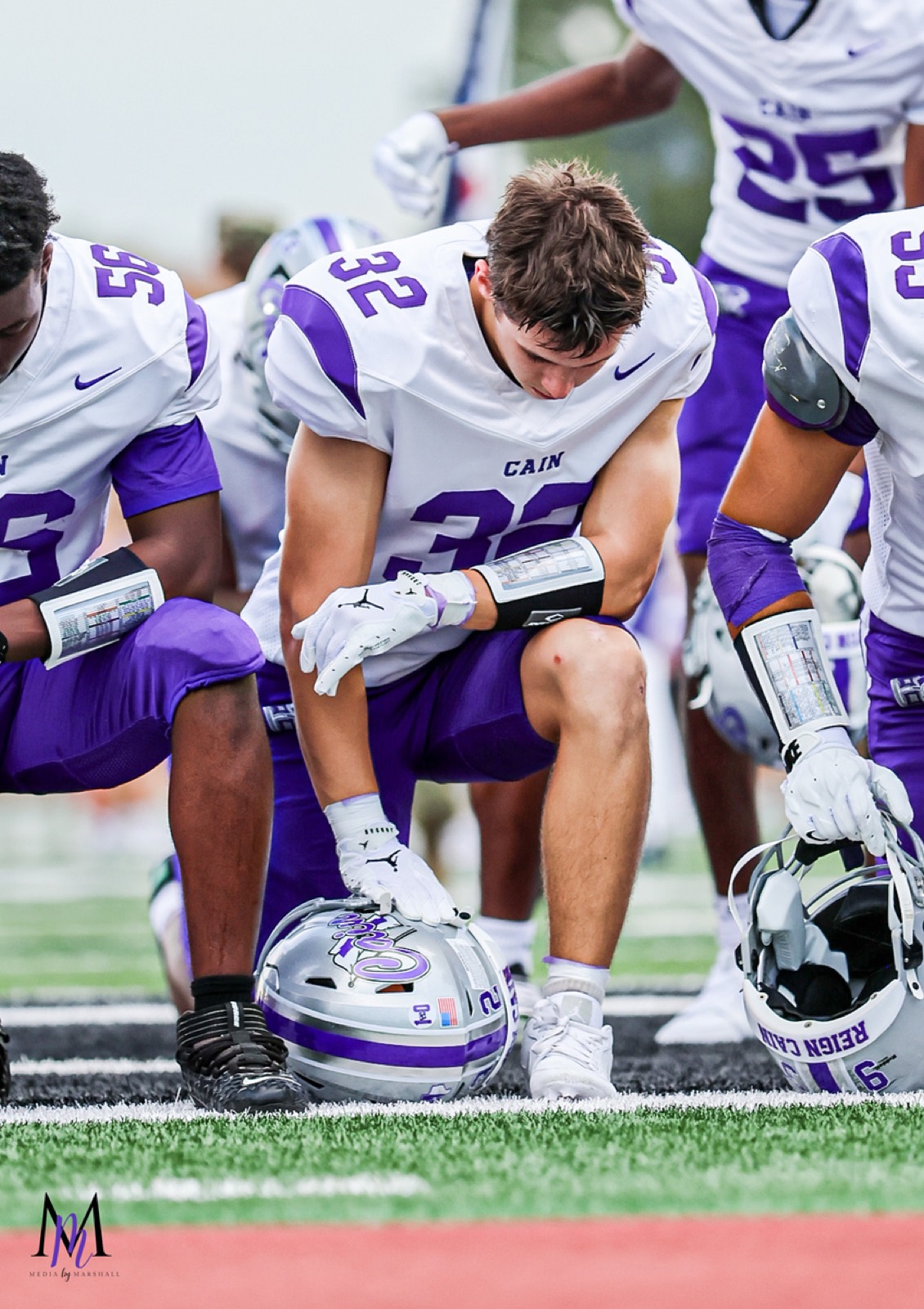 Senior linebacker Gage Hansberger kneels on the turf during pregame reflection