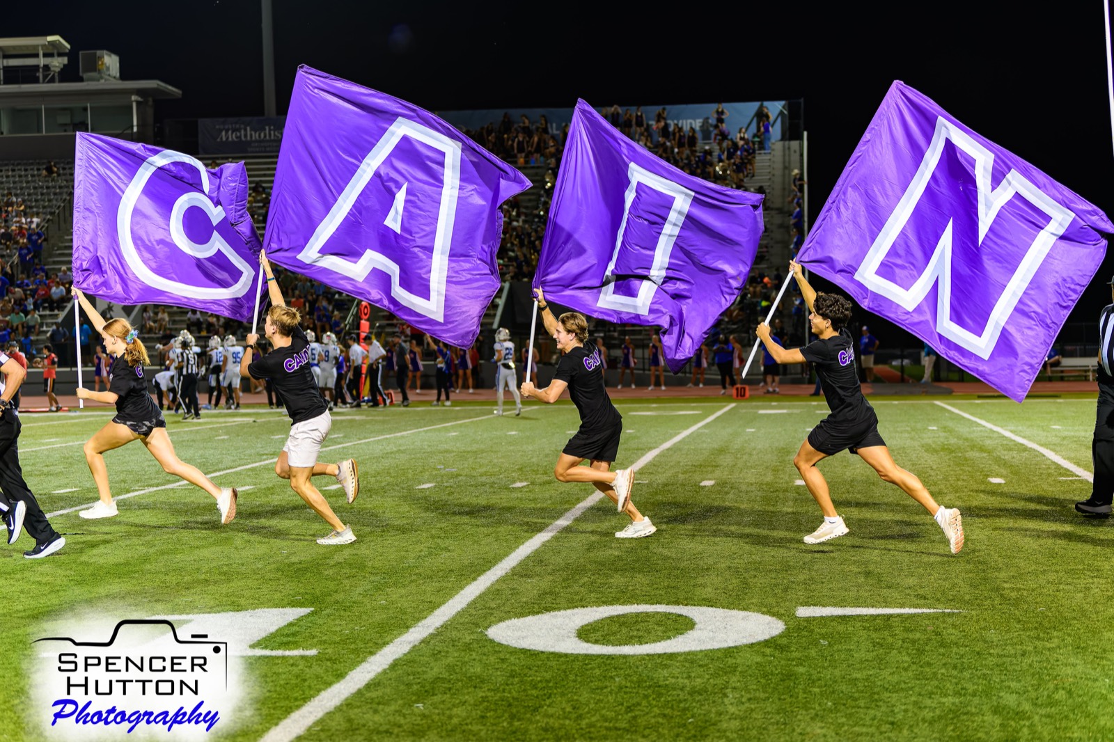 Klein Cain spirit crew runs with giant purple letters spelling CAIN across the field