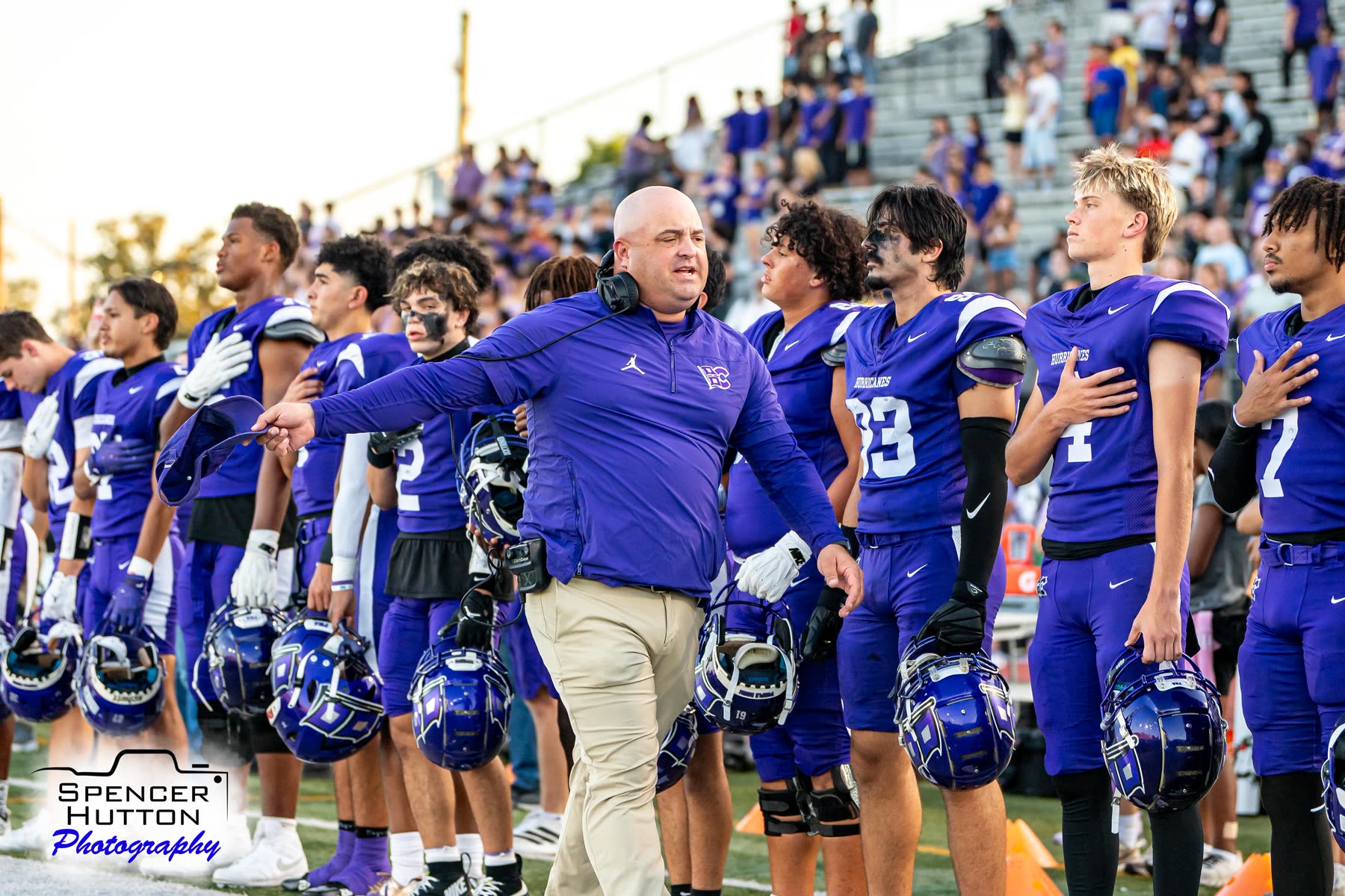 Head coach James Clancy and the Hurricanes stand along the sideline with hands over hearts during the national anthem