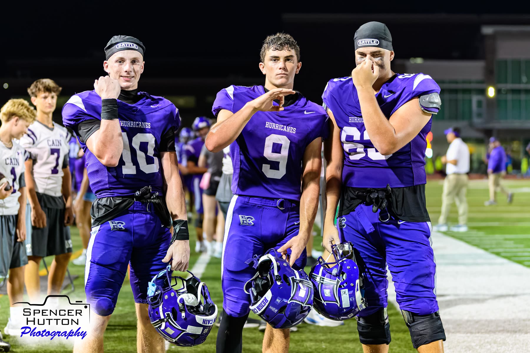Cooper Karns, Jace Hanks, and offensive lineman Clayton Rightmer pose on the sideline with their helmets